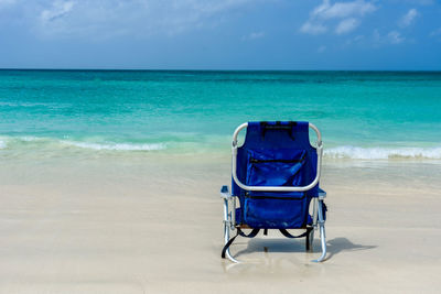 Deck chairs on beach against blue sky