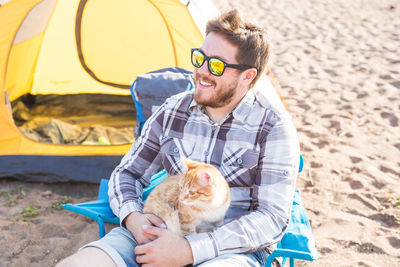 Man with cat wearing sunglasses while sitting outdoors
