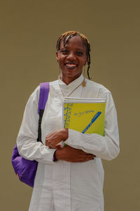 Portrait of a smiling young female african student carrying books and a bag