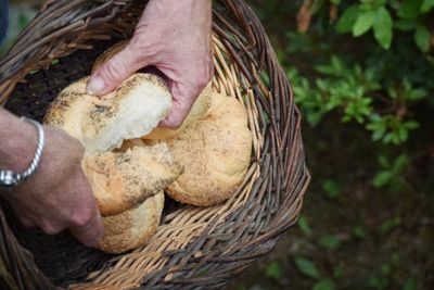 Cropped image of breaking bread in whicker basket