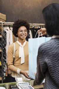 Saleswoman giving bag to happy customer at textile shop