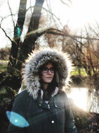 Close-up of young woman wearing fake fur against bare trees