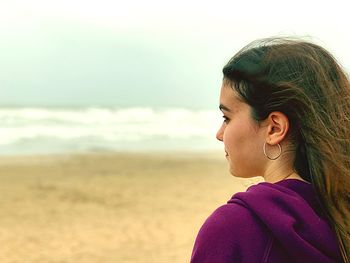 Portrait of woman looking away at beach against sky