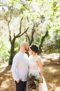 Man kissing woman while standing in forest