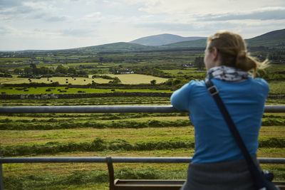 Rear view of woman standing on field against sky