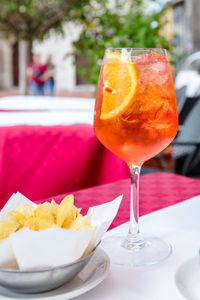 Glass of aperol spritz cocktail on outside table on sunny day 