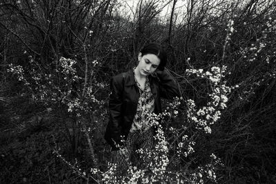 Young woman standing by tree in forest