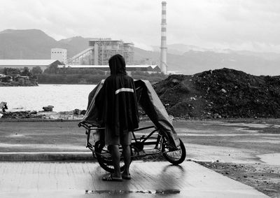 Rear view of woman with bicycle on road