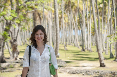 Portrait of smiling woman standing against trees