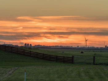 Scenic view of field against cloudy sky during sunset