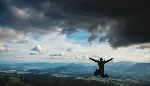 Man standing on landscape against cloudy sky