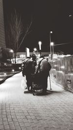 Rear view of people walking on illuminated street at night