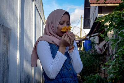 Side view of woman holding ice cream against built structure