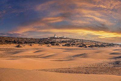 Beautiful sand dunes desert landscape against cloudy sky at sunset