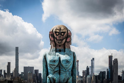 Statue of modern buildings against sky in city