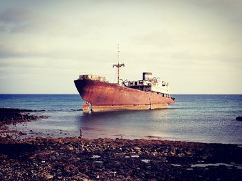 Abandoned ship moored on sea against sky