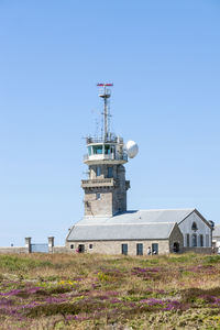 Low angle view of communications tower on field against clear sky