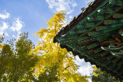 Low angle view of trees and building against sky