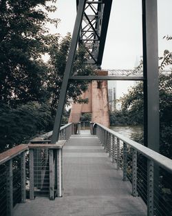 Footbridge over river against trees