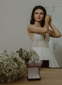 A beautiful bride dresses up in front of a mirror.