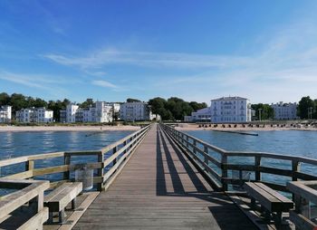 Pier over river in city against sky