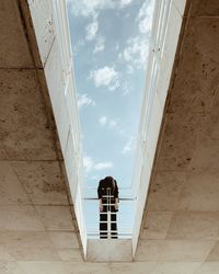 Low angle view of woman leaning on railing against sky