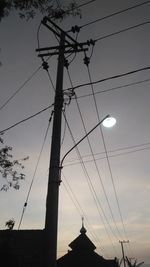 Low angle view of silhouette electricity pylon against sky