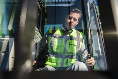 Man operating excavator at industrial plant on sunny day