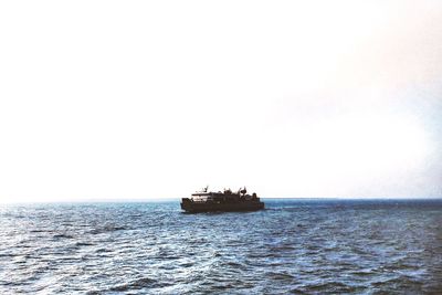 Boat sailing in sea against clear sky