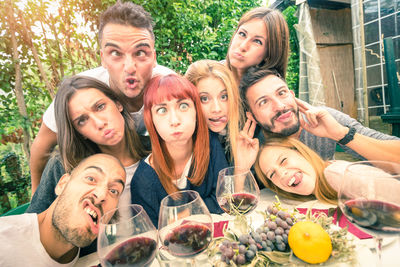 Portrait of friends making faces at dining table