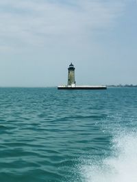 Lighthouse by sea against sky