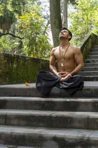 Young man doing meditation on a stairway in a forest, mexico