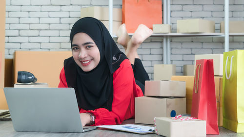 Young woman using mobile phone while sitting on table