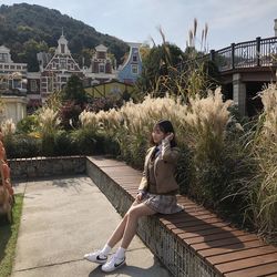 Full length of woman sitting against plants