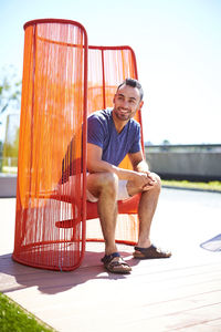 A man sitting outside in a colorful modern chair.