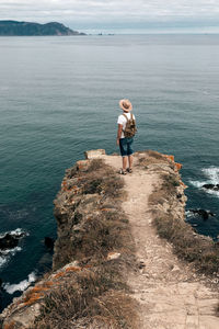 Man standing on rock looking at sea