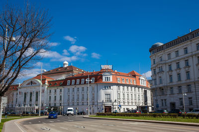 Road by buildings against blue sky