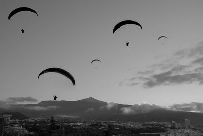 Silhouette person paragliding against sky