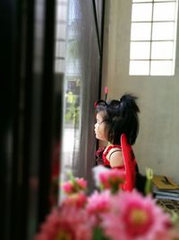 Side view of girl in angel costume looking towards window at home