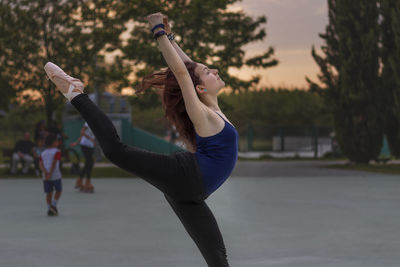 Side view of woman dancing ballet in park during sunset