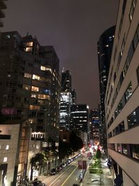 Illuminated city street and buildings against sky at night