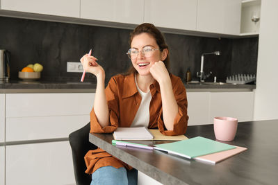 Portrait of young woman using mobile phone while sitting at home