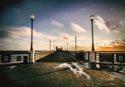 Bridge over street against sky during sunset