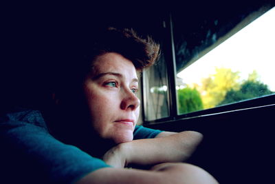 Mid adult woman looking through window at home