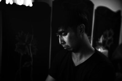 Close-up of thoughtful young man looking down while standing outdoors at night