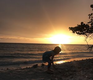 Man on beach against sky during sunset