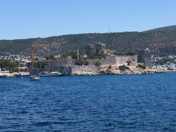 Scenic view of sea by buildings against clear blue sky