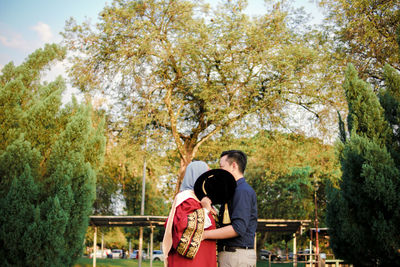 Rear view of man and woman standing by trees