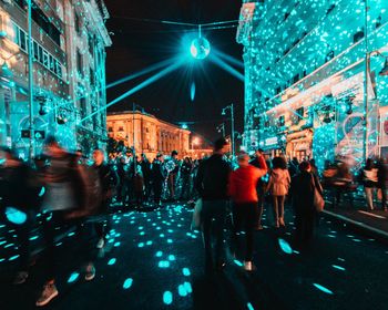 People on illuminated street in city at night