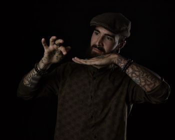 Young man looking away while standing against black background